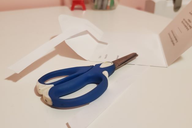 A picture showing a scissor cutting a piece of paper