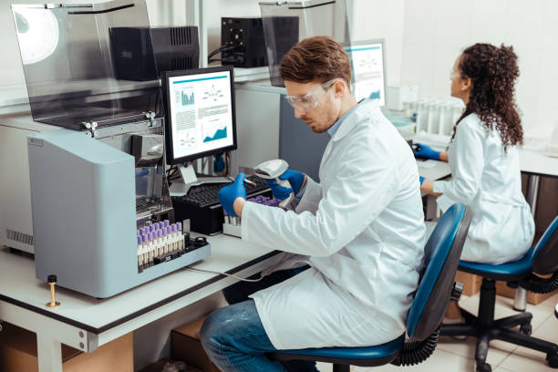 A picture showing two lab personnel working instrument and samples