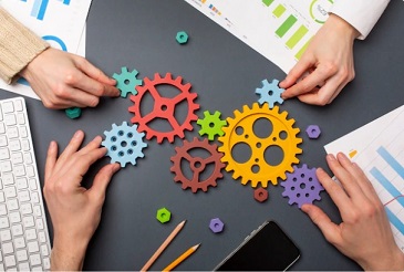 picture showing a set of different size of gears arranged by two pairs of hands